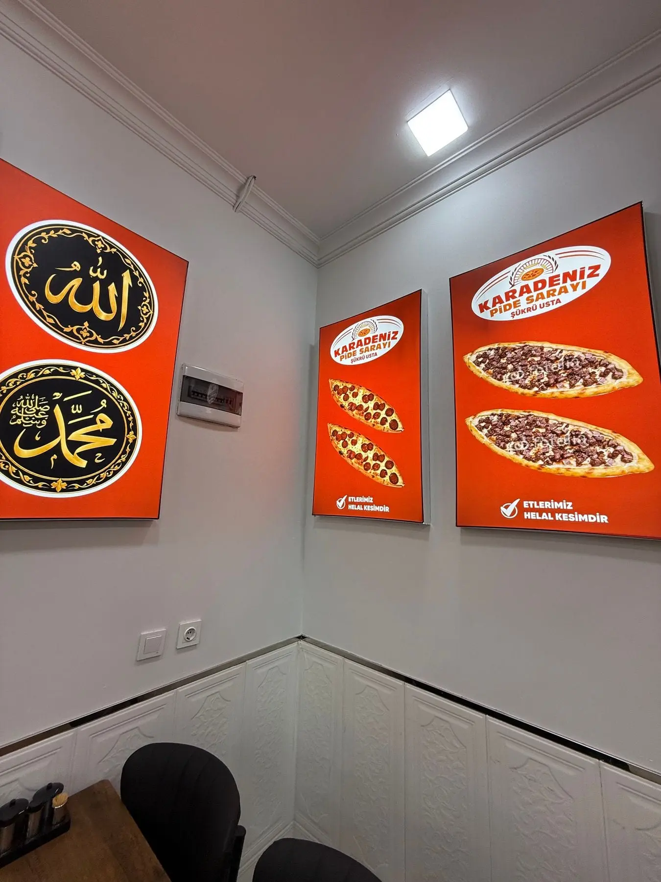 Dükkânın içi: duvarda pide fotoğrafları ve hat levhaları