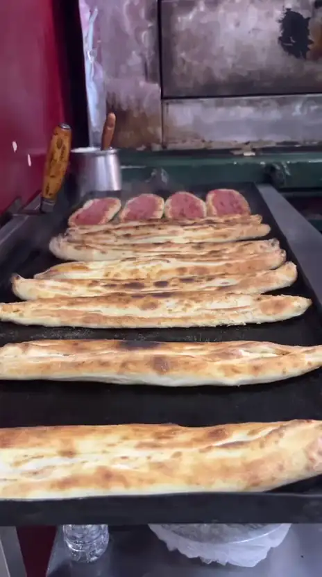 Fırından çıkan pidelere fırçayla tereyağı sürülüyor